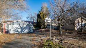 View of yard with a detached garage, an outbuilding, and driveway