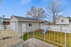 Wooden terrace with a fenced backyard, an outdoor structure, and a playground