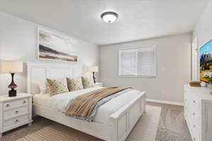 Bedroom featuring a textured ceiling and light carpet