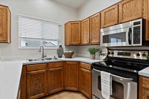 Kitchen featuring stainless steel appliances, brown cabinetry, light countertops, and light wood-style floors