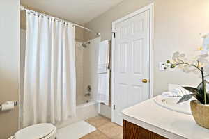 Bathroom with vanity, shower / bath combination with curtain, a textured ceiling, and light tile patterned floors