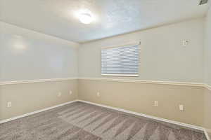 Empty room with a textured ceiling and carpet flooring