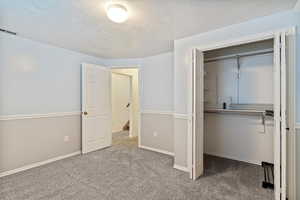 Unfurnished bedroom featuring a closet, a textured ceiling, and carpet flooring