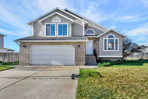View of front facade featuring stucco siding, a garage, driveway, and brick siding