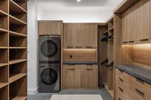Laundry room featuring stacked washing machine and dryer and light tile patterned floors
