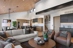 Living room featuring wooden ceiling, recessed lighting, bar area, high vaulted ceiling, and stairway
