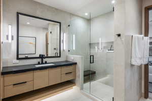 Ensuite bathroom with vanity, a stall shower, recessed lighting, and tile walls