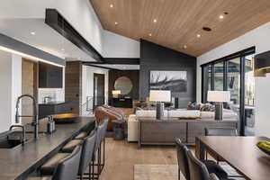 Living area featuring wood ceiling, recessed lighting, an accent wall, light wood finished floors, and high vaulted ceiling