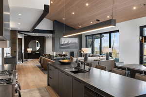 Kitchen featuring modern cabinets, open floor plan, stainless steel range with gas stovetop, wooden ceiling, and light wood-style flooring