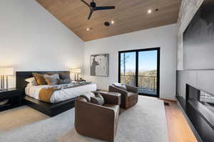 Bedroom with access to exterior, a fireplace, light wood-style flooring, high vaulted ceiling, and wooden ceiling