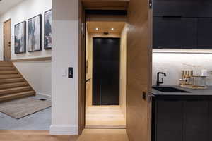 Hall with light wood finished floors and recessed lighting