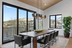 Dining room featuring a chandelier, light wood-type flooring, vaulted ceiling, wooden ceiling, and a mountain view