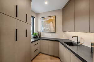Kitchen with light wood finished floors, dark stone counters, gray cabinets, and modern cabinets