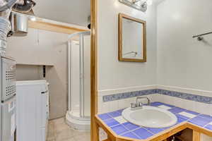 Full bathroom with washer / dryer, a shower stall, tile patterned floors, and vanity