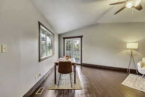 Unfurnished dining area featuring vaulted ceiling, dark wood finished floors, and a ceiling fan