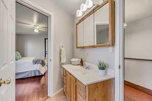 Ensuite bathroom with vanity, light wood-style floors, and ceiling fan