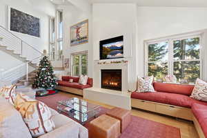 Living area with high vaulted ceiling, stairs, wood finished floors, and a glass covered fireplace
