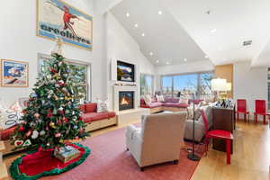 Living area with high vaulted ceiling, recessed lighting, wood finished floors, a glass covered fireplace, and beam ceiling