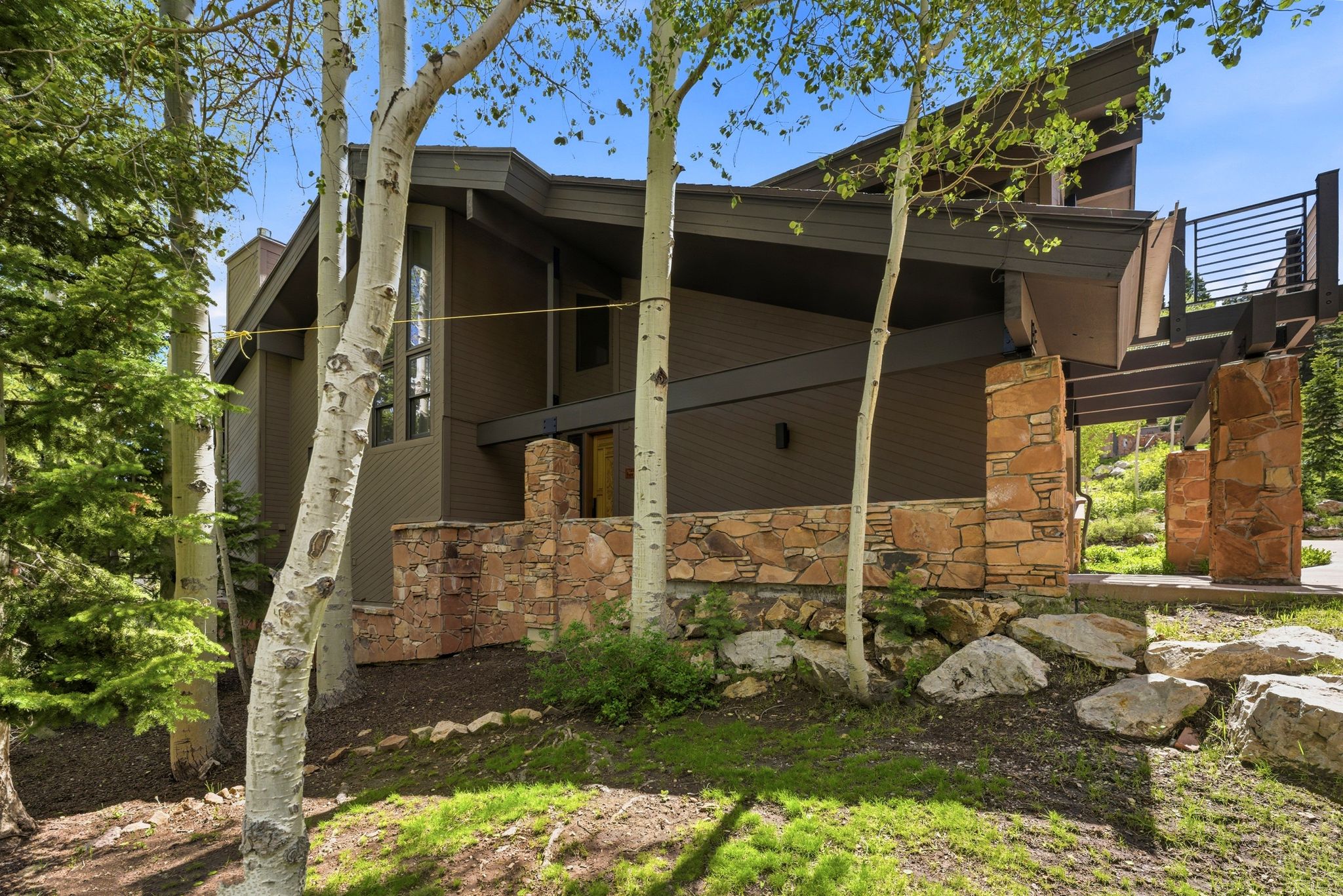 Modern architectural design with a dark brown exterior, stone facade accents, and a distinctive angled roofline