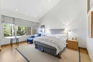 Bedroom featuring high vaulted ceiling, light wood-style floors, and recessed lighting