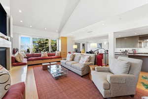 Living area with recessed lighting, wood finished floors, a fireplace, and high vaulted ceiling