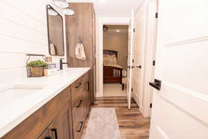 Ensuite bathroom with double vanity, light wood finished floors, and recessed lighting