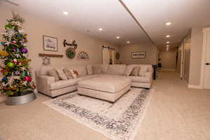 Living area featuring a barn door, light carpet, and recessed lighting