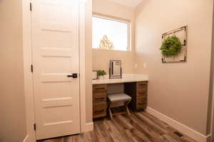 Office area featuring built in study area and dark wood finished floors