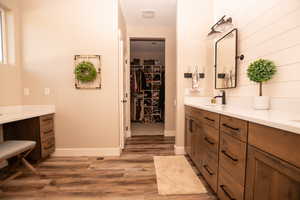 Bathroom with double vanity, a spacious closet, and light wood-type flooring