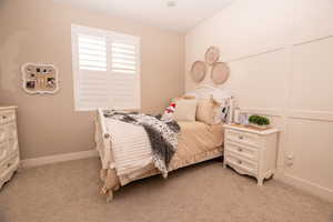 Bedroom with a decorative wall and light carpet