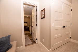 Corridor featuring light colored carpet and baseboards