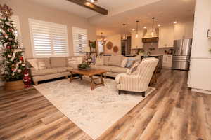 Living area with wood finished floors, beamed ceiling, a chandelier, and recessed lighting