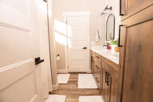 Bathroom featuring double vanity, a shower with shower curtain, and light wood-style floors