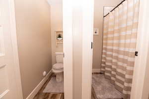 Bathroom with a shower with curtain and dark wood-style flooring