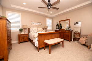 Bedroom with a tray ceiling, light carpet, recessed lighting, and ceiling fan