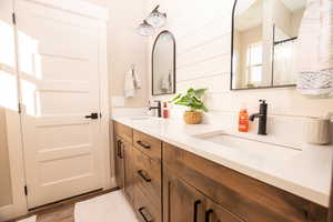 Bathroom with double vanity, light wood-style floors, and a shower with curtain