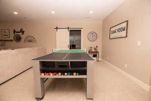 Recreation room featuring a barn door, light carpet, and recessed lighting
