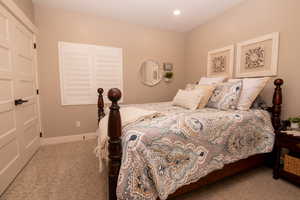 Bedroom with light colored carpet and a closet