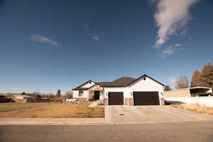 Modern farmhouse style home with board and batten siding, driveway, a garage, and stone siding