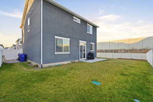 Back of property at dusk with a fenced backyard, a patio area, and stucco siding