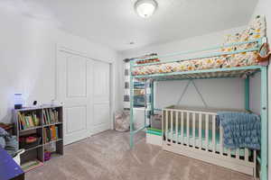 Bedroom with light colored carpet and a closet