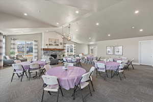 Carpeted dining area with a stone fireplace, recessed lighting, and high vaulted ceiling
