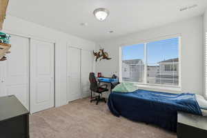 Bedroom with multiple closets, light carpet, and an office area
