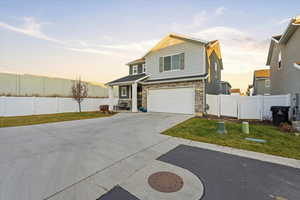 View of front of property featuring driveway, stone siding, an attached garage, and a gate