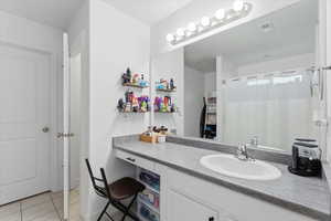 Bathroom featuring curtained shower, vanity, and light tile patterned floors