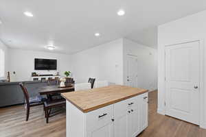 Kitchen featuring butcher block counters, white cabinetry, light wood-style flooring, recessed lighting, and open floor plan