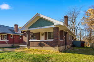 View of front of property with a chimney, brick siding, and a porch