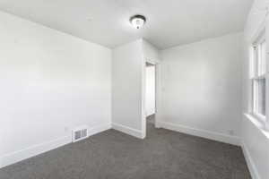 Spare room with dark carpet and baseboards