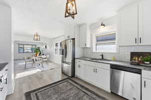 Kitchen featuring a chandelier, light stone countertops, stainless steel appliances, white cabinets, and a textured ceiling