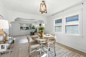 Dining room with arched walkways, light wood finished floors, and healthy amount of natural light